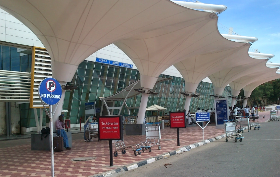 Chauffeur-driven Ertiga taxi waiting outside the terminal for Coimbatore airport pickup and drop services.
